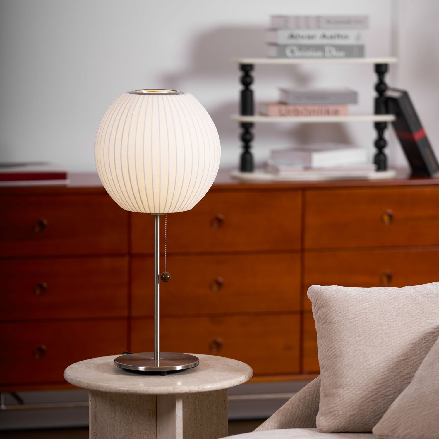 Faux silk bubble table lamp with chrome stem lit warmly on a side table