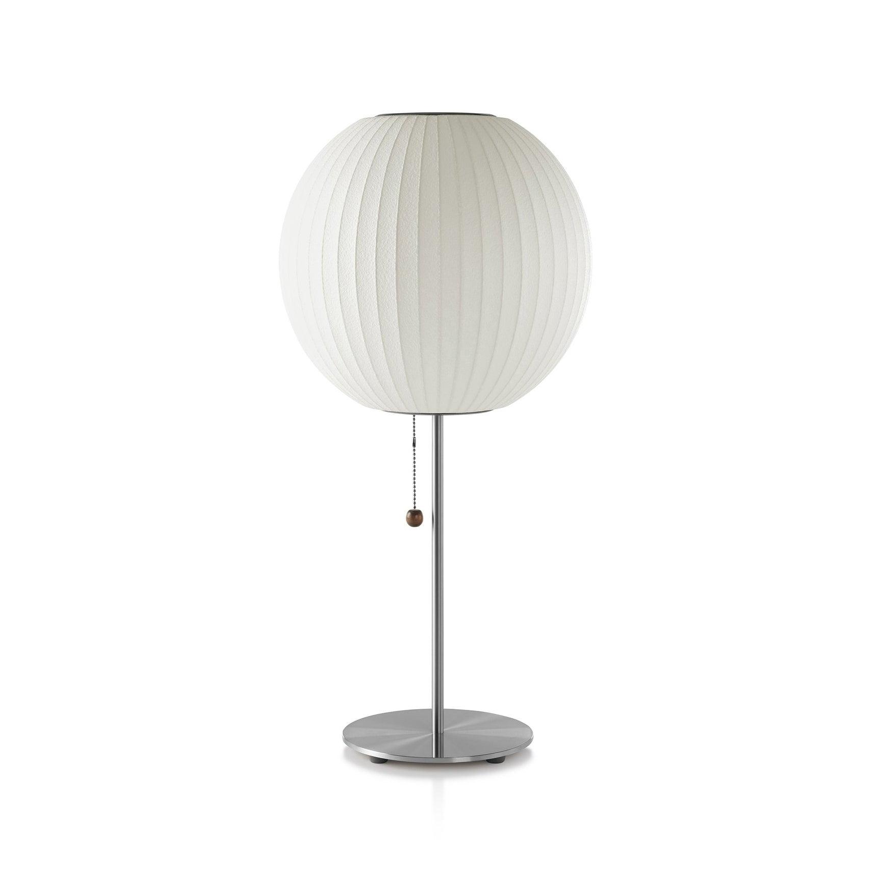 Faux silk bubble table lamp with chrome stem lit warmly on a side table