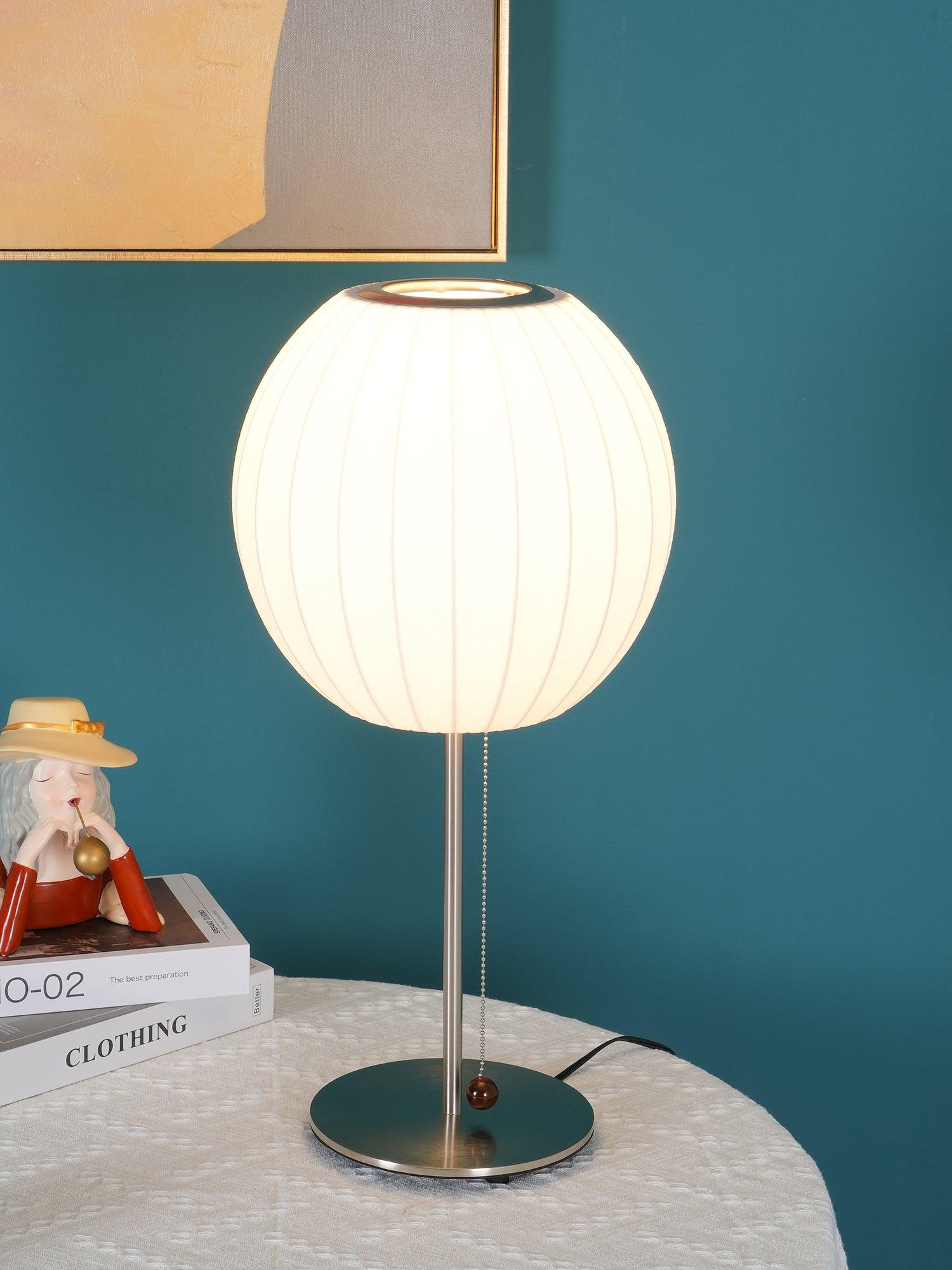 Chrome-stemmed faux silk bubble table lamp glowing in a cosy living room