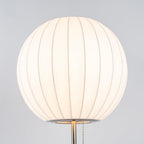Chrome-stemmed faux silk bubble table lamp glowing in a cosy living room