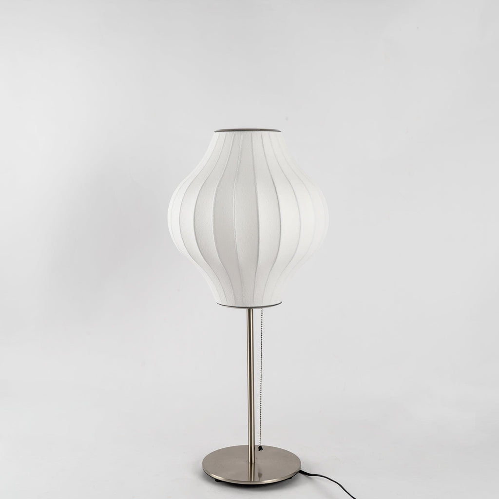 Faux silk bubble table lamp with chrome stem lit warmly on a side table