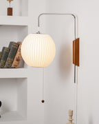 Round white wall sconce with chrome bracket against textured wall