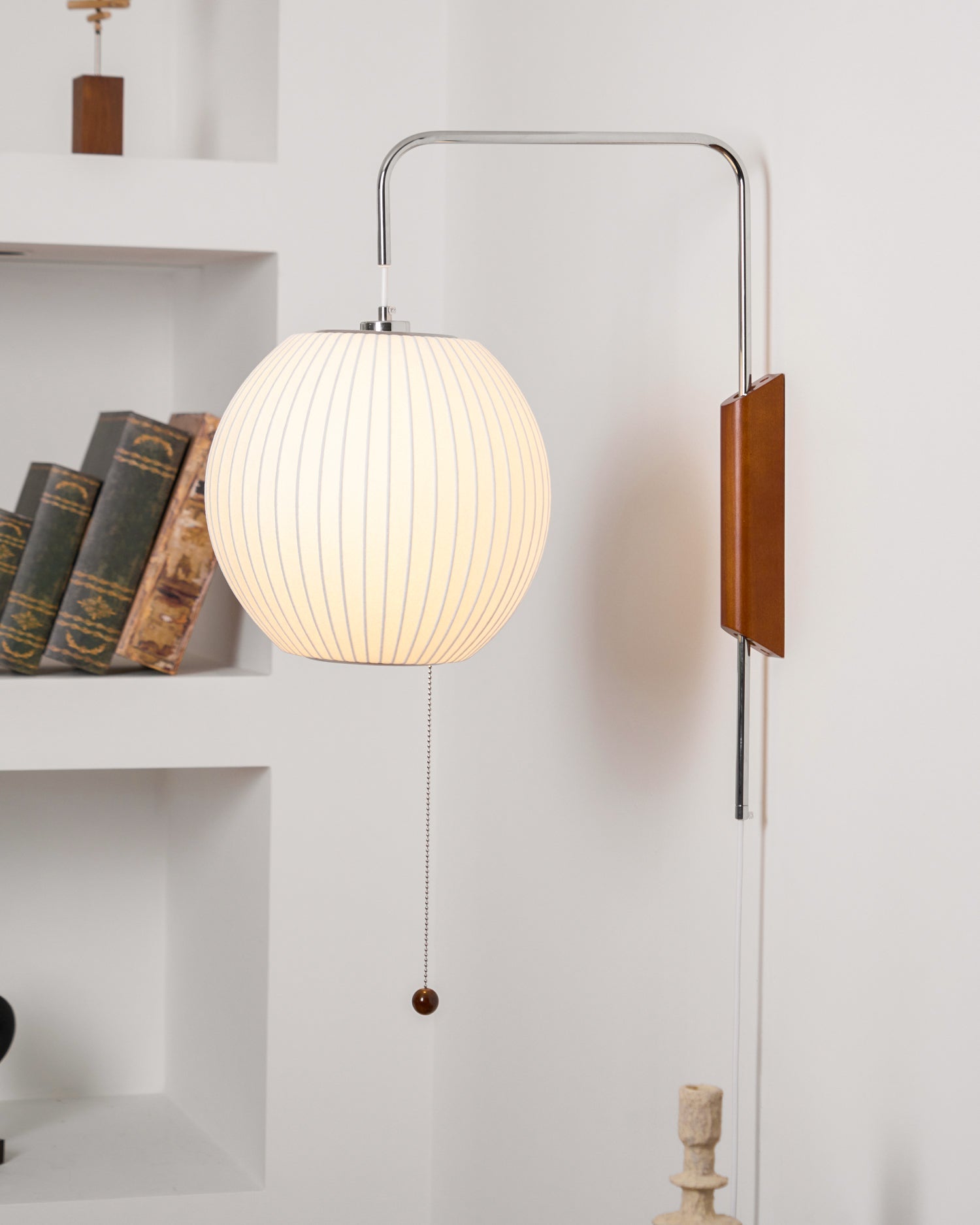 Round white wall sconce with chrome bracket against textured wall