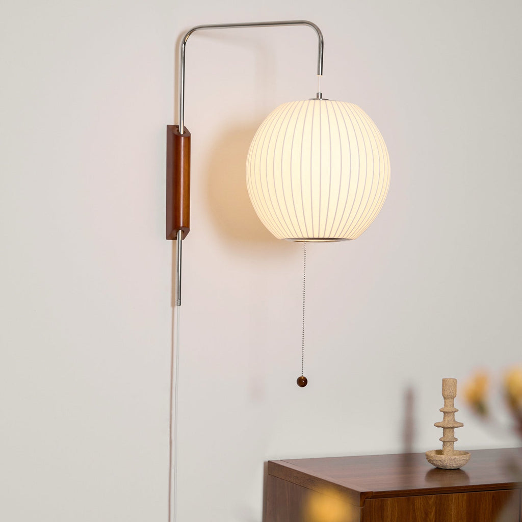 White ball wall sconce shown angled on swivel hinge near seating