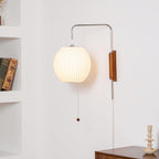White sphere wall sconce mounted beside framed art on wall