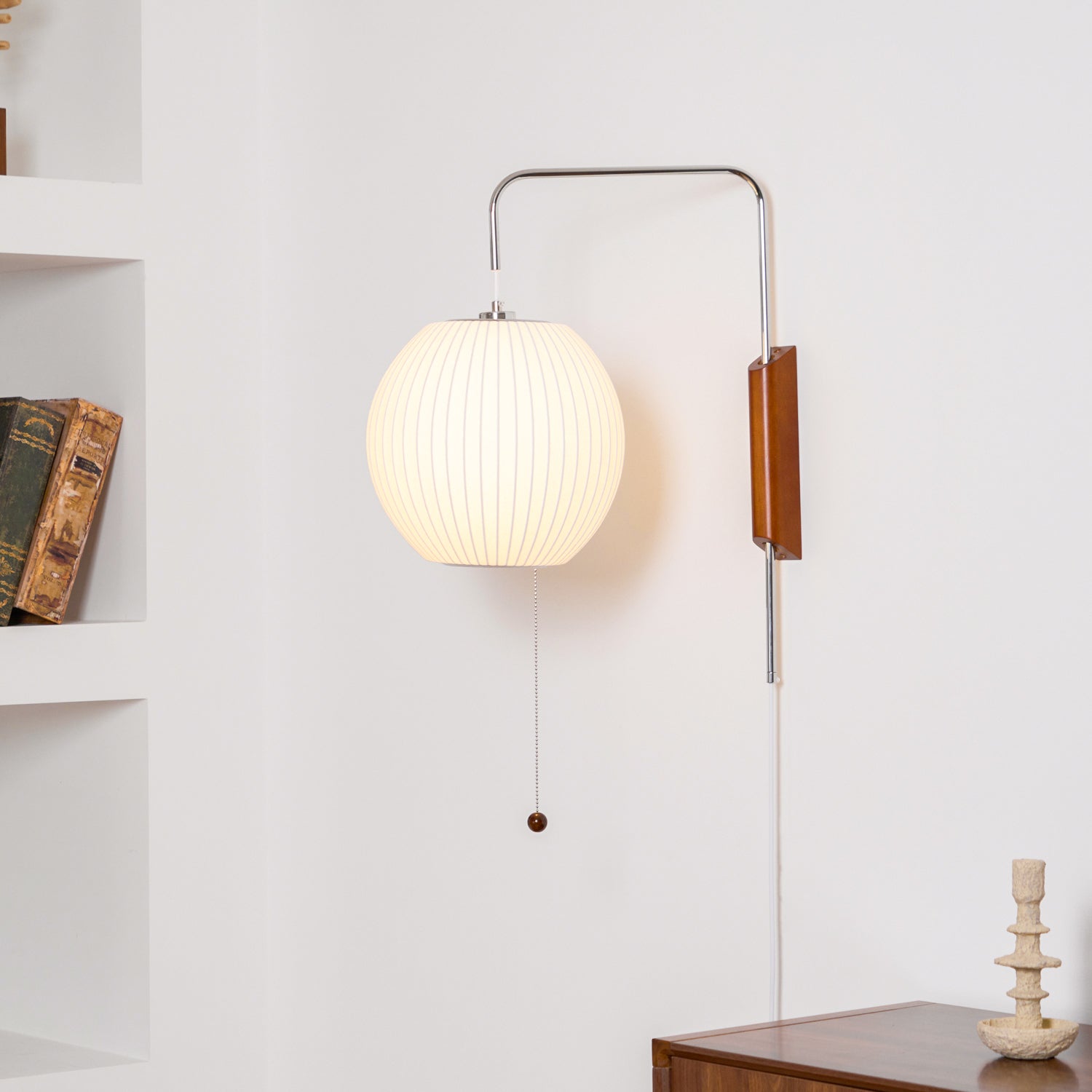 White sphere wall sconce mounted beside framed art on wall