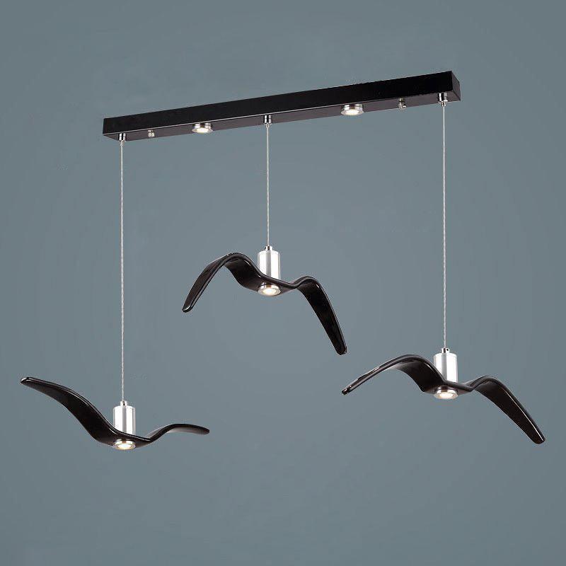 Three black bird-shaped pendants from this Clérachic fixture hang at staggered lengths from a black linear canopy.