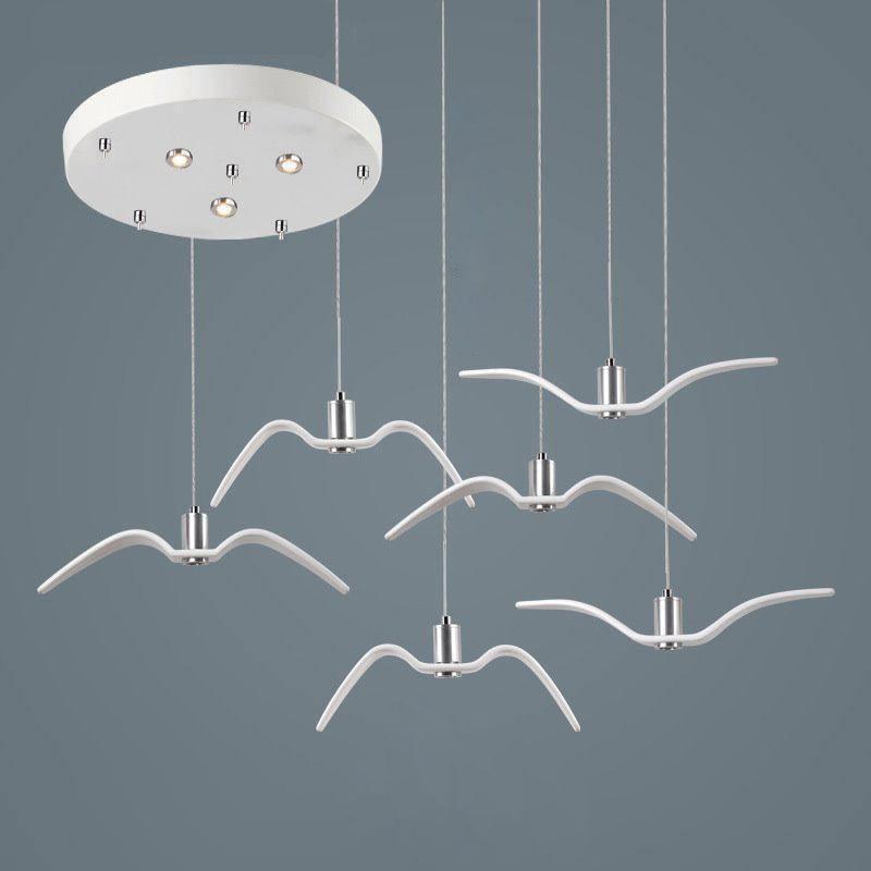 Six white bird-shaped pendants from this Clérachic fixture hang at staggered lengths from a round white canopy.