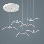 Six white bird-shaped pendants from this Clérachic fixture hang at staggered lengths from a round white canopy.