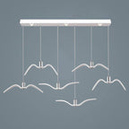 Six white bird-shaped pendants from this Clérachic fixture hang at staggered lengths from a white linear canopy, seen from above.