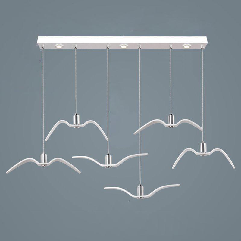 Six white bird-shaped pendants from this Clérachic fixture hang at staggered lengths from a white linear canopy, seen from above.