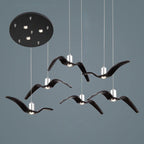 Six black bird-shaped pendants from this Clérachic fixture hang at staggered lengths from a round black canopy.