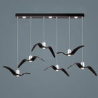 Six black bird-shaped pendants from this Clérachic fixture hang at staggered lengths from a black linear canopy.