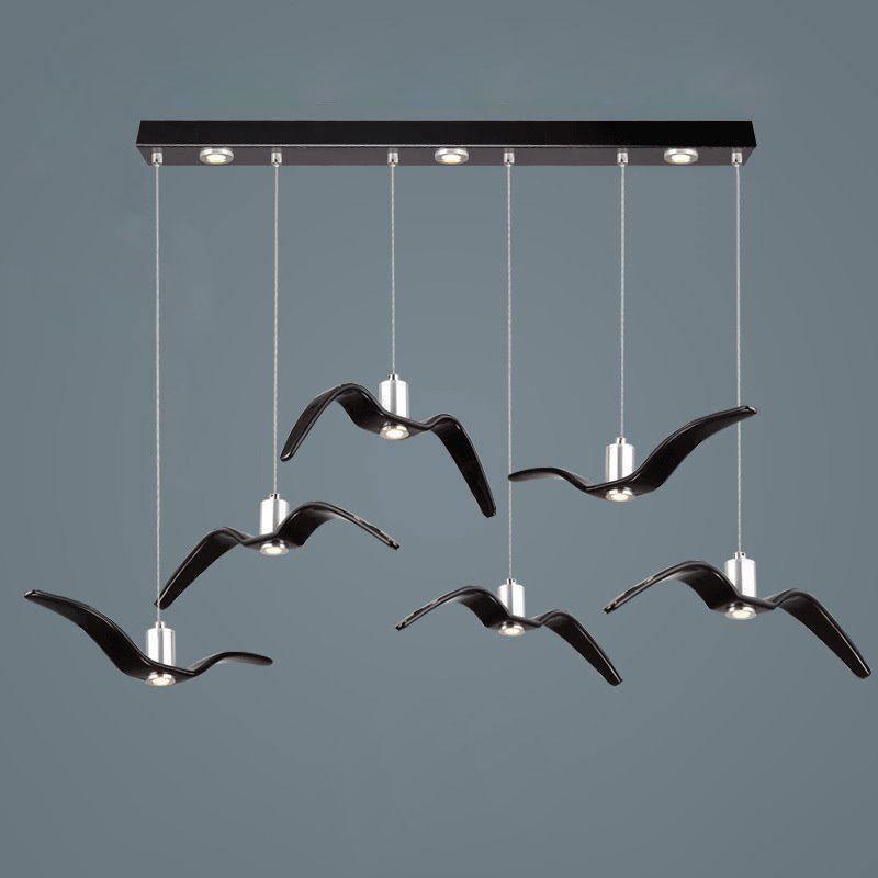 Six black bird-shaped pendants from this Clérachic fixture hang at staggered lengths from a black linear canopy.