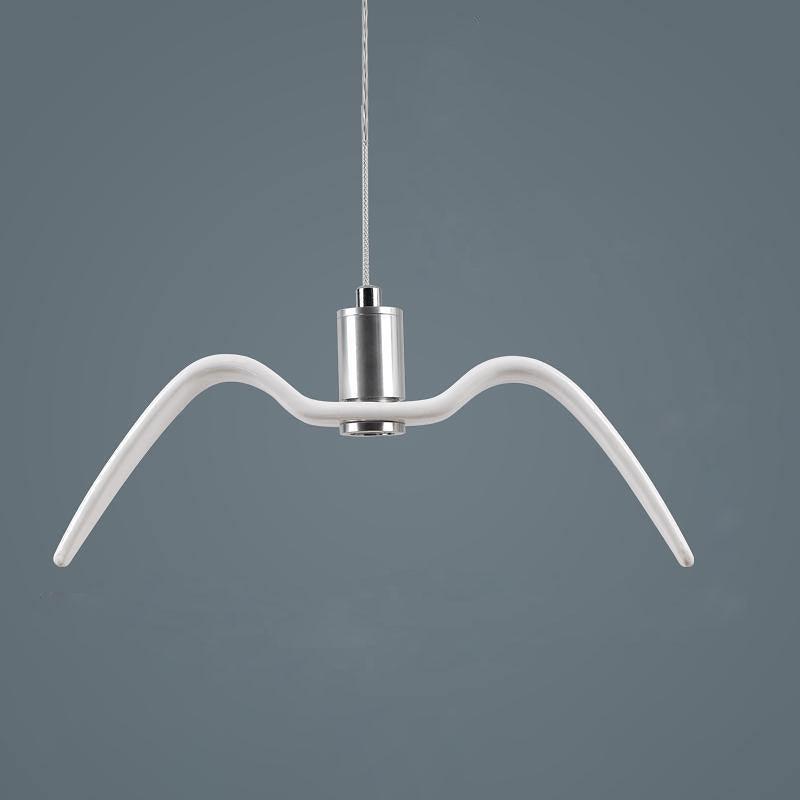 A white bird-shaped pendant from this Clérachic light hangs front-on with wings spread, its nickel neck catching the light against a dark blue-grey backdrop.