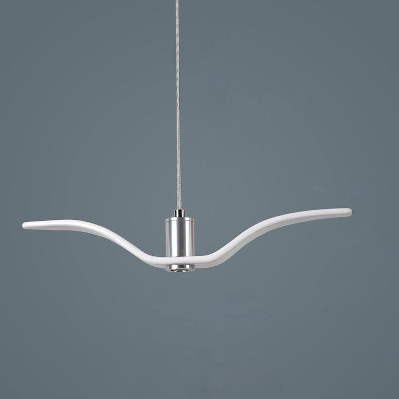 A white bird-shaped pendant from this Clérachic fixture is seen in profile, its slim wings extended, on a dark blue-grey backdrop.