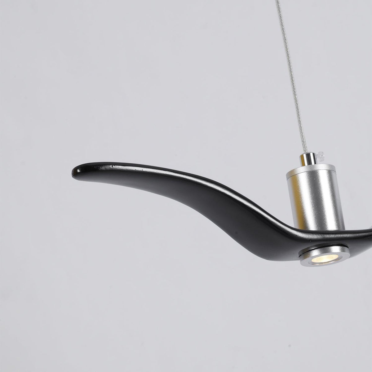 Close view of the nickel neck joint on this black Clérachic bird pendant, its LED lit.