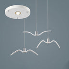 Three white bird-shaped pendants from this Clérachic fixture hang from a round white canopy, on a slate-blue backdrop.