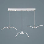 Three white bird-shaped pendants from this Clérachic fixture hang at staggered lengths from a white linear canopy.