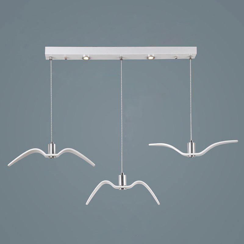 Three white bird-shaped pendants from this Clérachic fixture hang at staggered lengths from a white linear canopy.