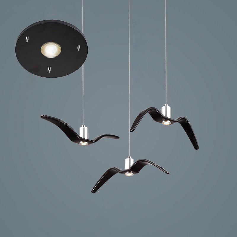 Three black bird-shaped pendants from this Clérachic fixture hang from a round black canopy, seen close against a dark blue-grey backdrop.