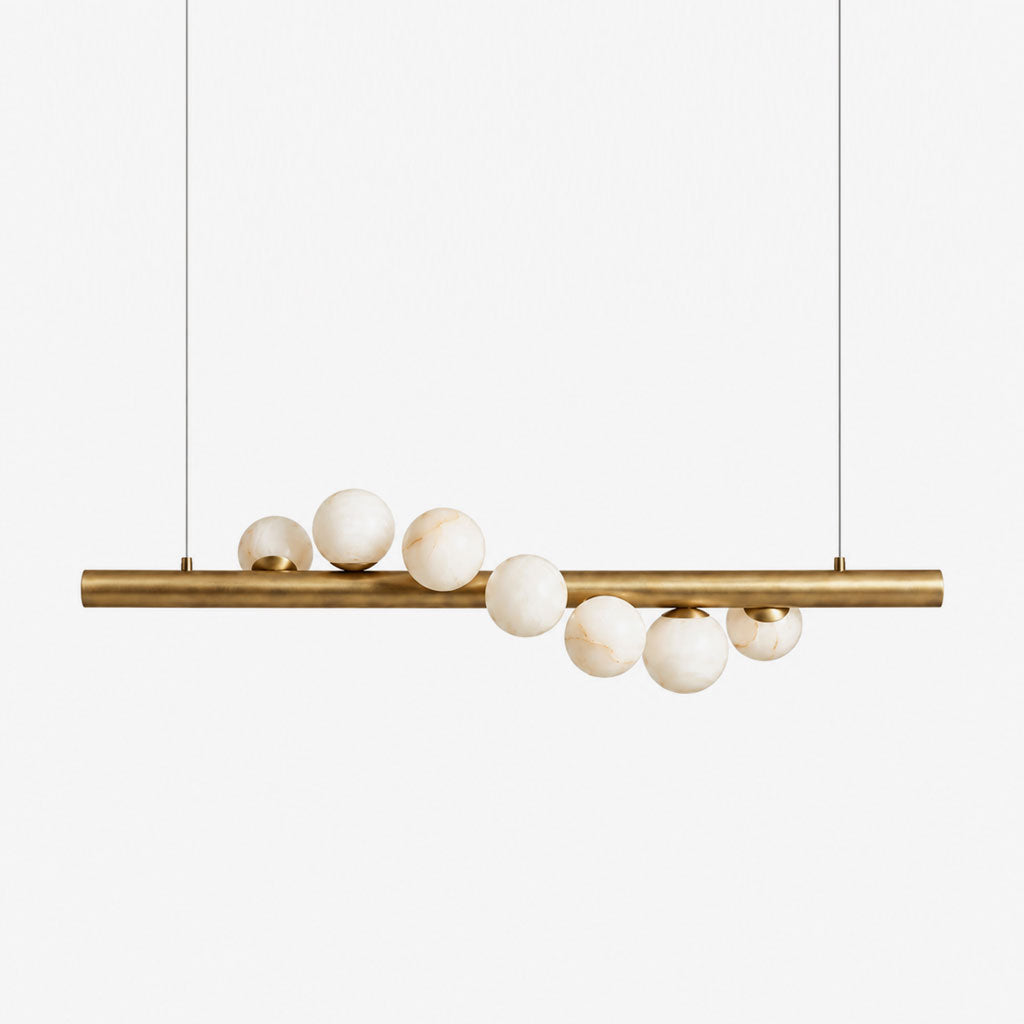 Angled view on a plain background, the alabaster spheres of this Clérachic pendant cluster unevenly along a brushed brass bar.