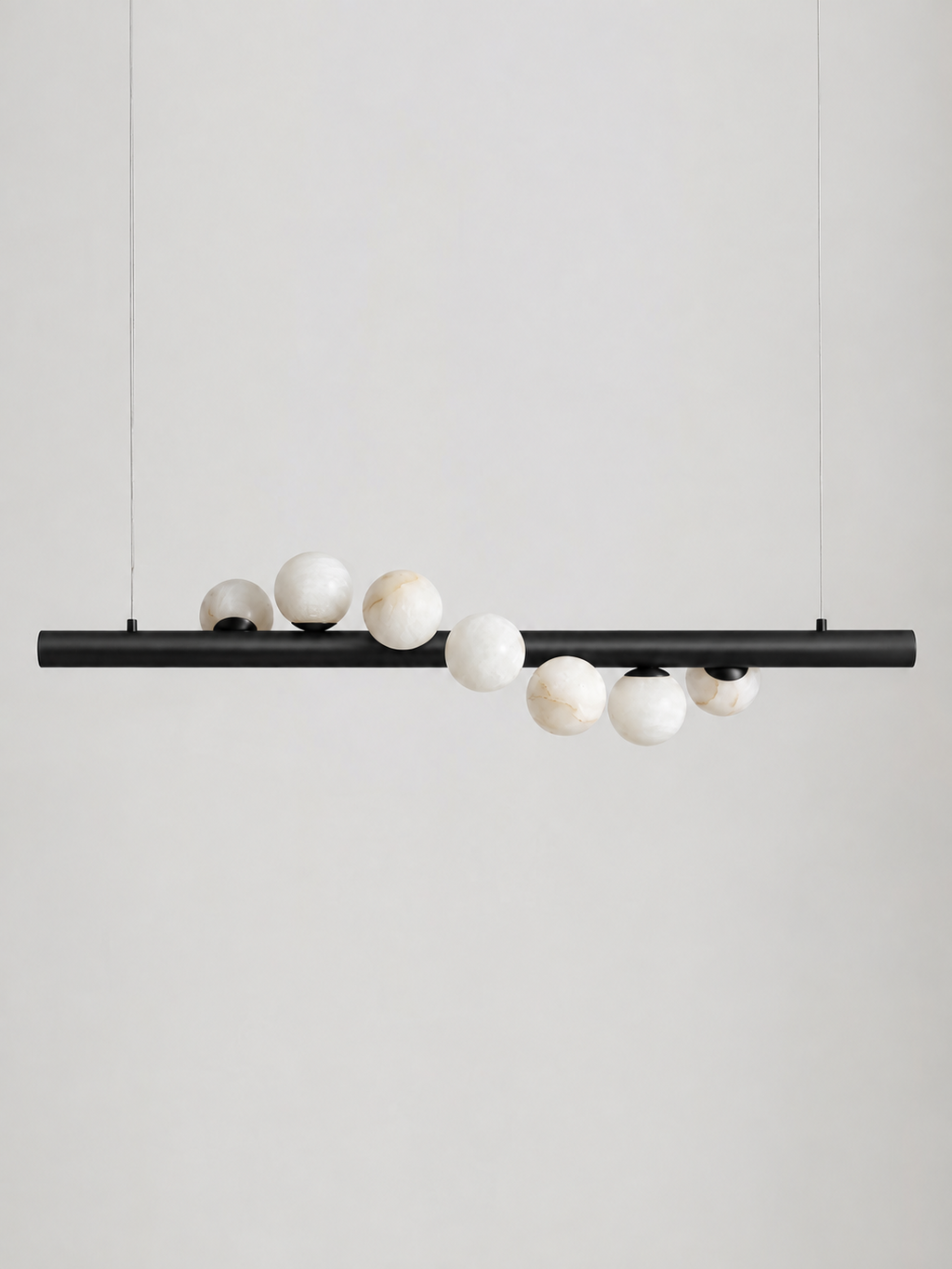 Studio shot on a bare background, this Clérachic pendant's matte black bar holds alabaster spheres clustered along its length.