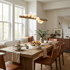 In a sunlit window nook, this Clérachic pendant in brushed brass hangs over a table with caramel leather chairs.