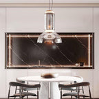 This Clérachic pendant hangs over a marble dining table in front of a black stone backsplash lit with a thin gold strip.