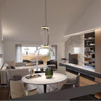 A single glowing cylinder from this Clérachic pendant lights a round marble table in an open living space.