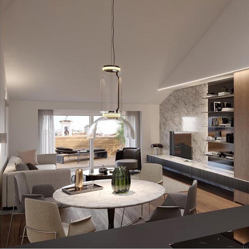 A single glowing cylinder from this Clérachic pendant lights a round marble table in an open living space.