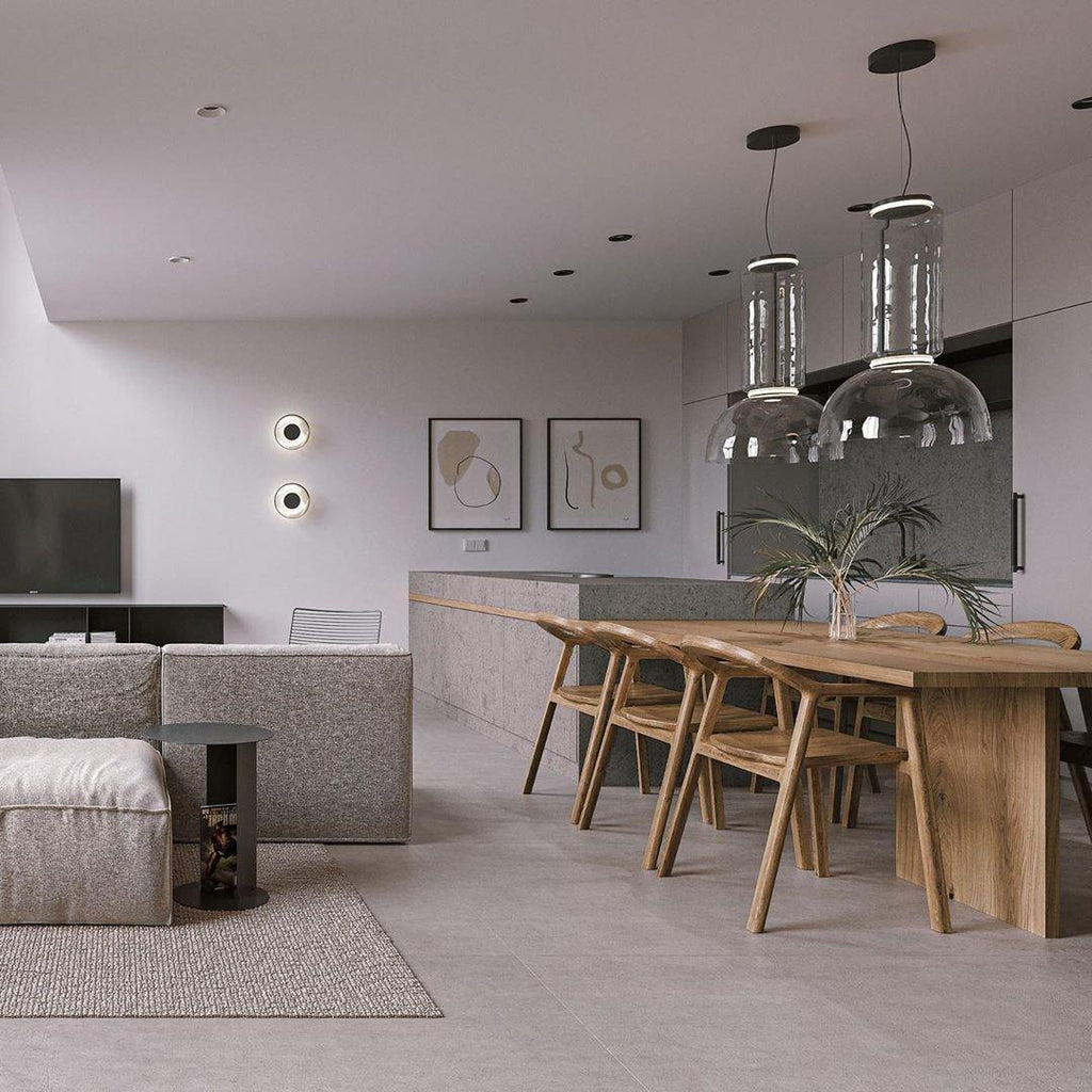 Two cylinder-shaded pendants from this Clérachic collection line up above a wood dining table in an open kitchen.
