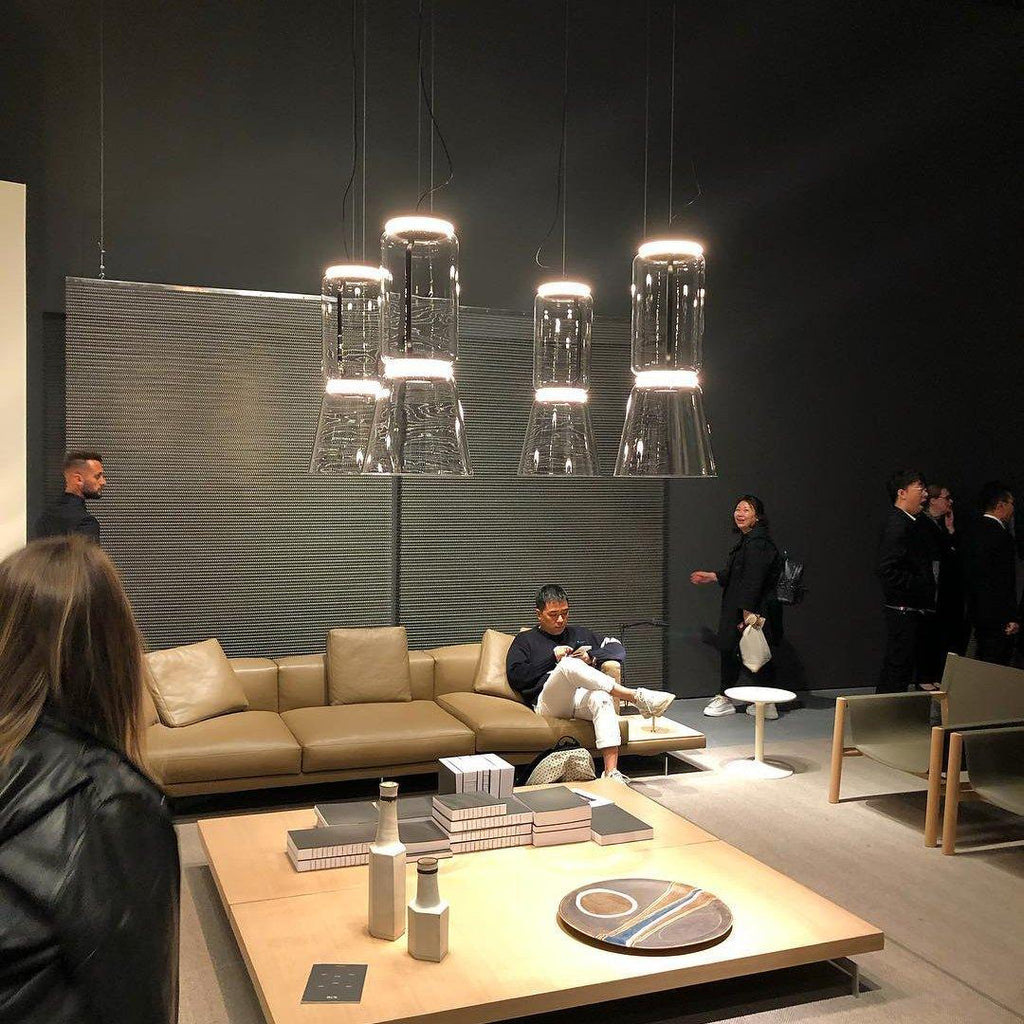 A cluster of glowing cone-shaped pendants from this Clérachic collection hangs above a showroom seating area.