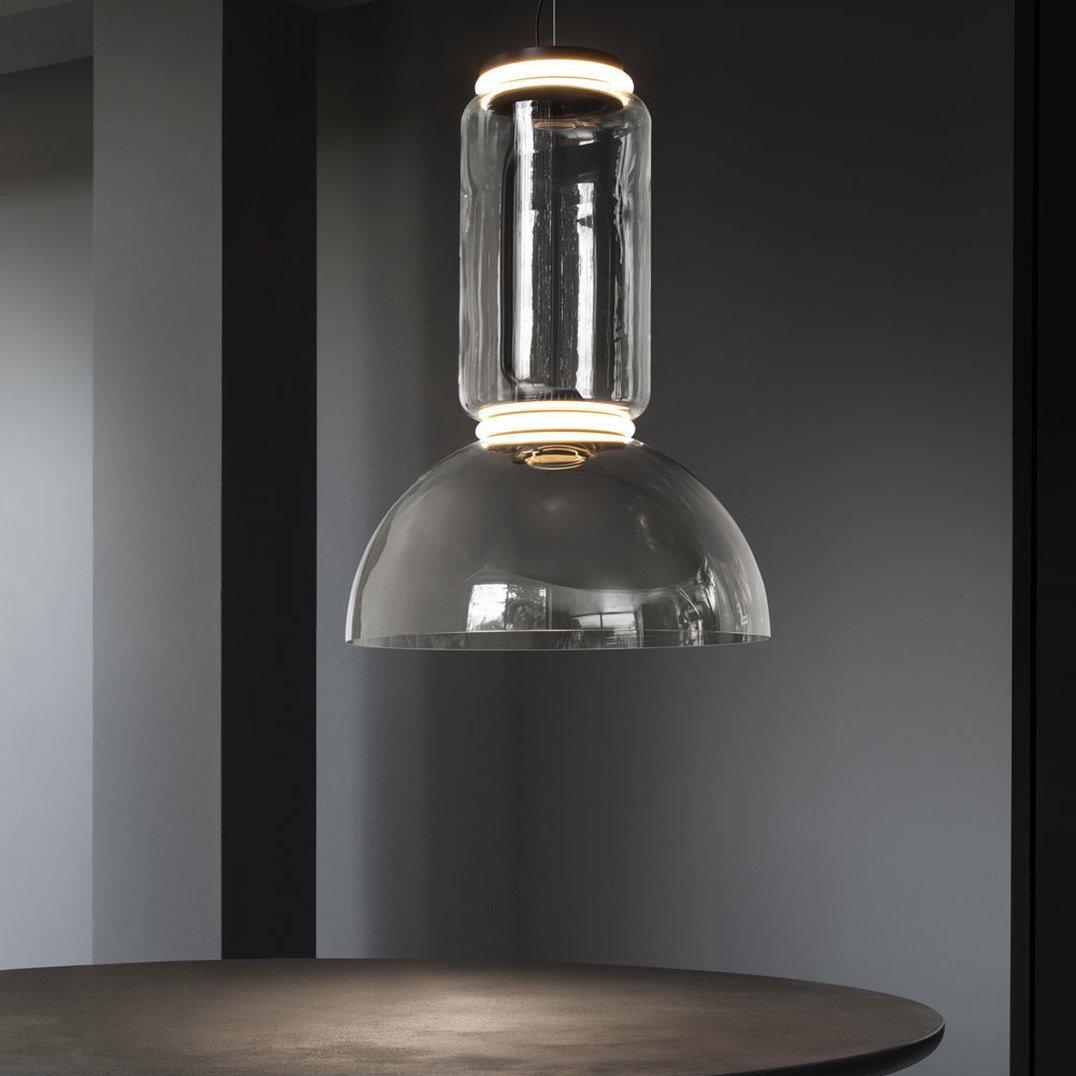 A single dome-shaped clear-glass shade on this Clérachic pendant hangs low above a round table.