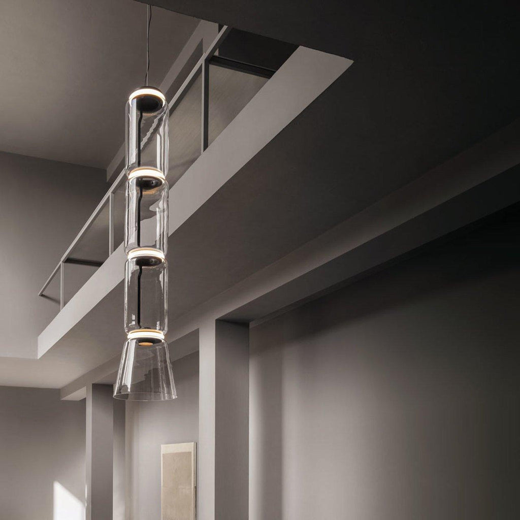 Four stacked cylinders of this Clérachic pendant glow warm beneath an angled ceiling beam.