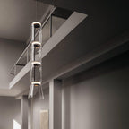 Four stacked cylinders of this Clérachic pendant glow warm beneath an angled ceiling beam.