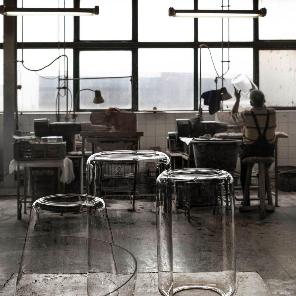 Unlit clear-glass shades for this Clérachic pendant sit on a workbench in a glass-blowing workshop.