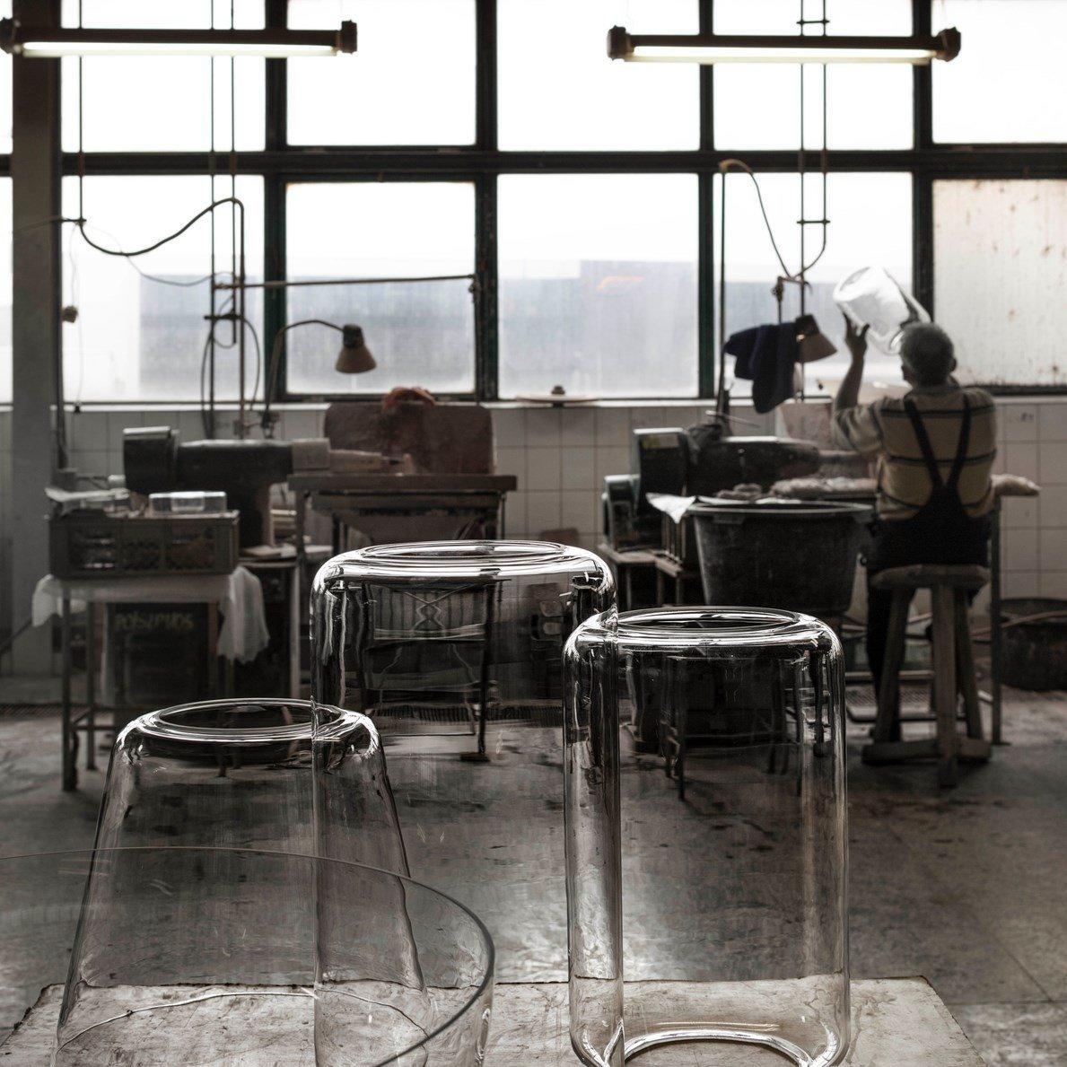 Unlit clear-glass shades for this Clérachic pendant sit on a workbench in a glass-blowing workshop.