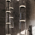 A dense cluster of glowing glass cylinders from this Clérachic pendant hangs against a weathered fresco wall.