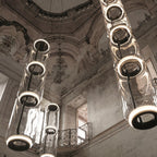 Close view of this Clérachic pendant's black-ringed cylinders against an ornate frescoed ceiling.