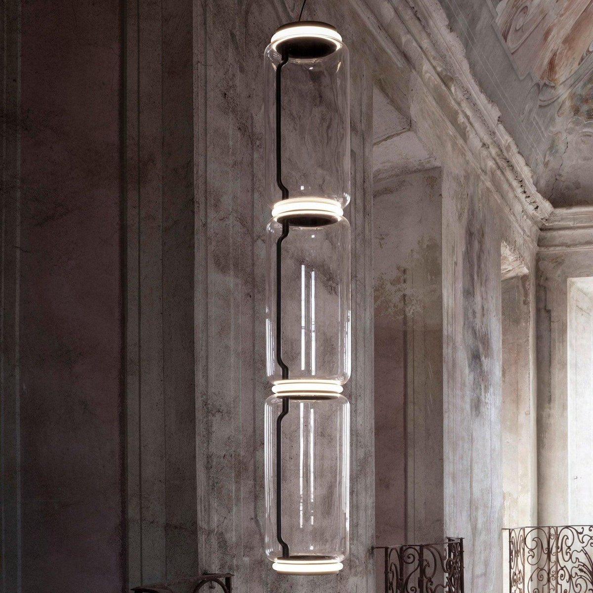 A single stack of five glowing cylinders from this Clérachic pendant lights a weathered stately room.