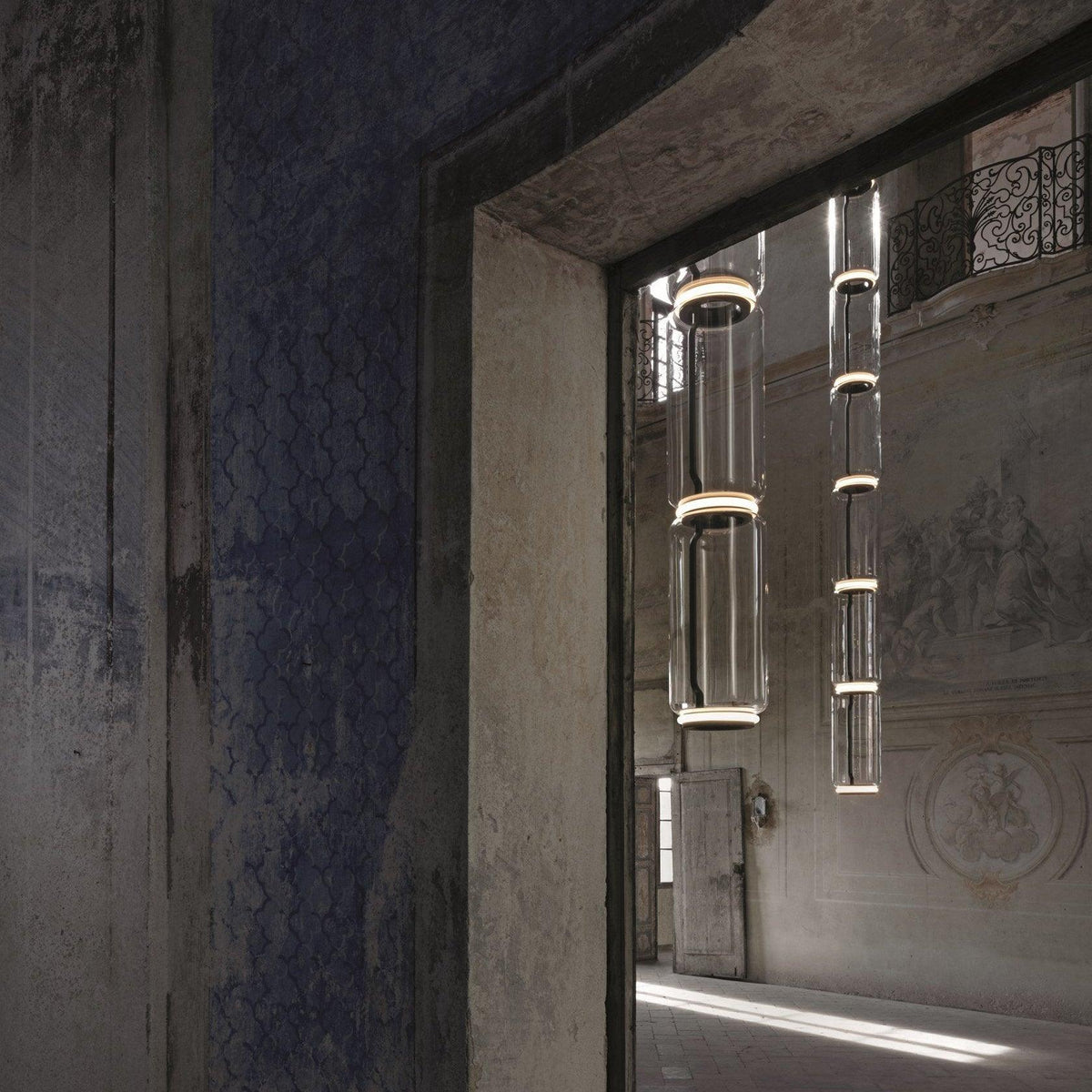 Two cylinder stacks of this Clérachic pendant hang beside a stone archway in a period doorway.
