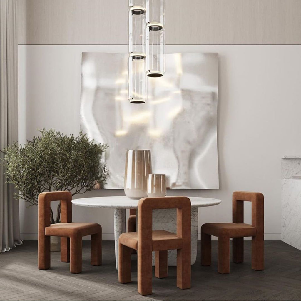 This Clérachic pendant's clustered cylinders hang above a marble-topped table beside patterned dining chairs.