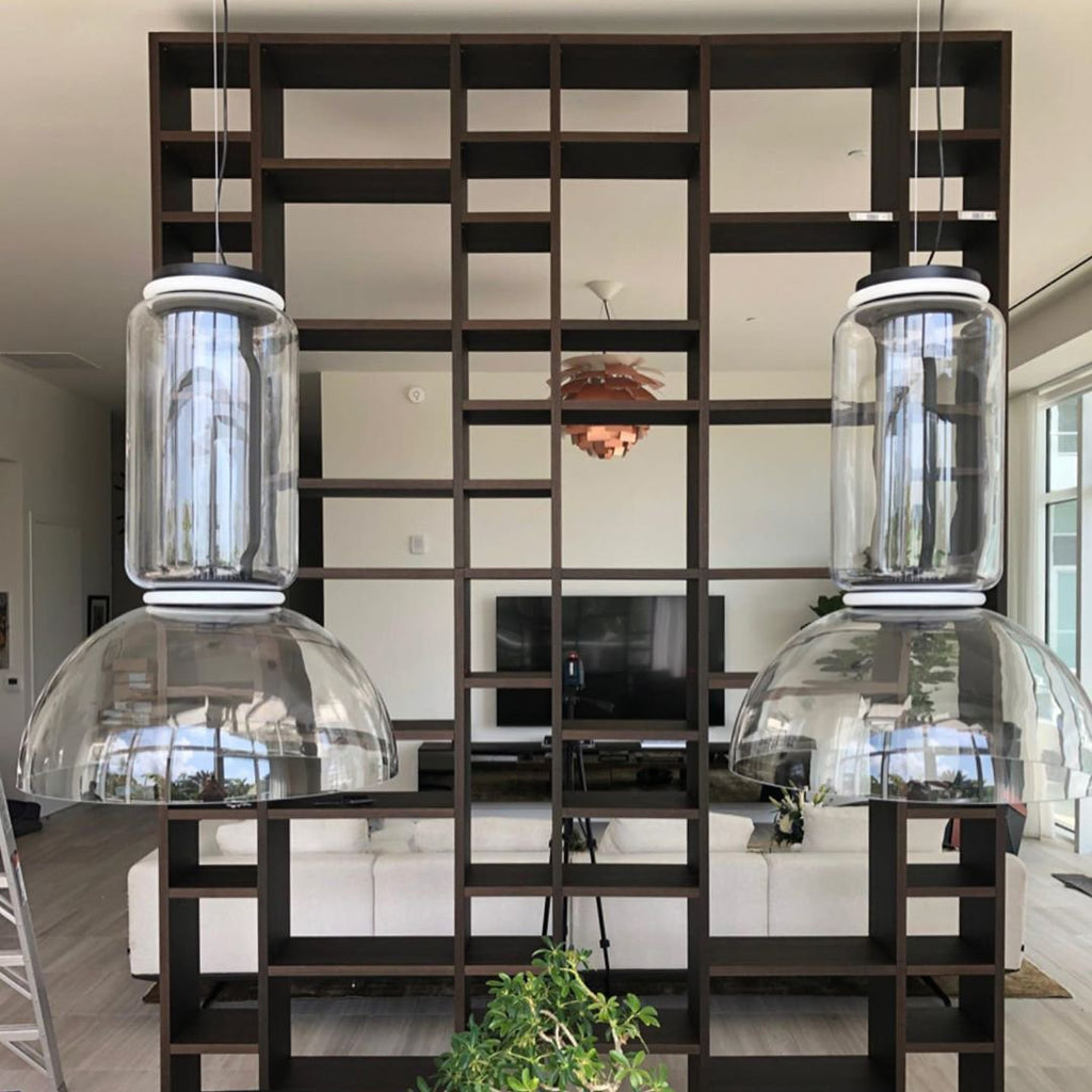 Two dome-shaded pendants from this Clérachic collection hang from an open shelving divider above a television console.