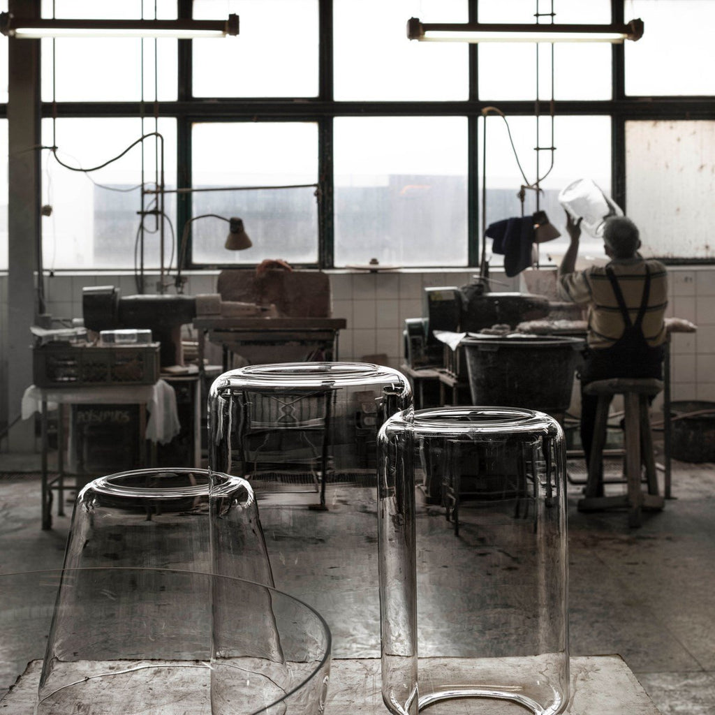 Unlit glass shades for this Clérachic pendant stand on stools in a glass-blowing workshop.
