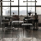 Unlit glass shades for this Clérachic pendant stand on stools in a glass-blowing workshop.