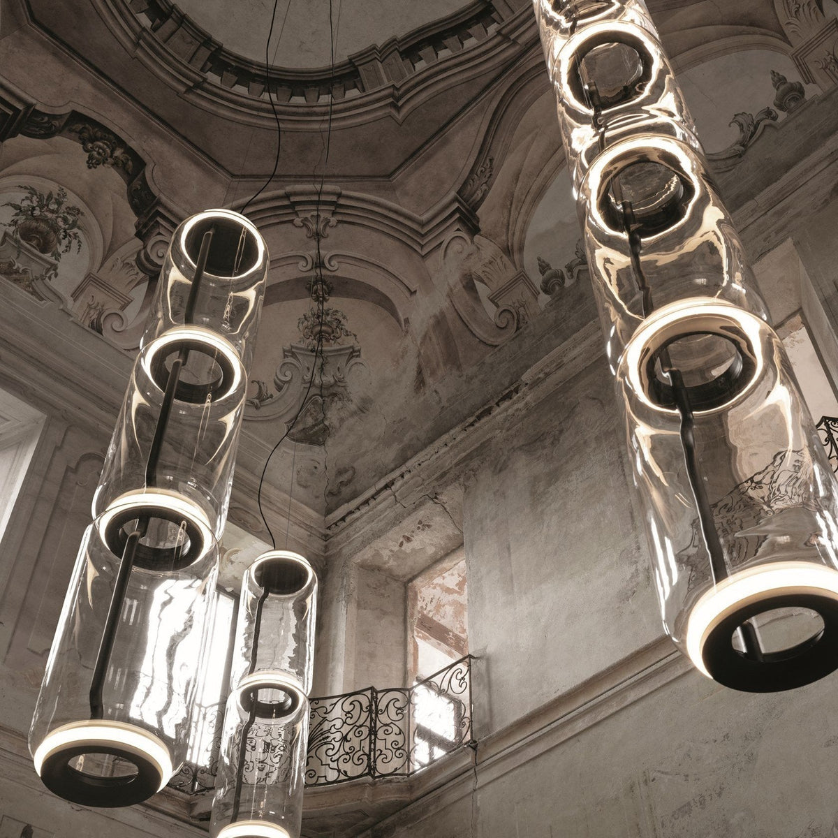 Close view of several cylinder clusters from this Clérachic pendant beneath an ornate frescoed dome ceiling.