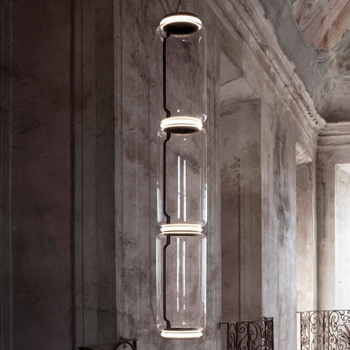 Close view of a three-cylinder stack from this Clérachic pendant against a weathered fresco wall.