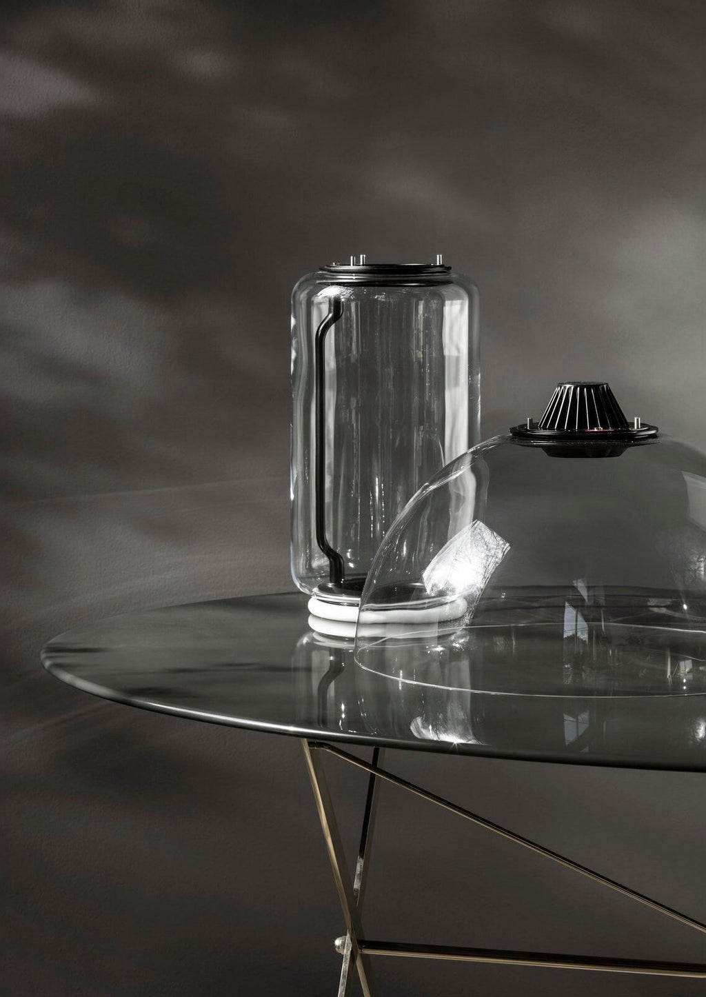 Close view of one glass cylinder from this Clérachic pendant fitted with its black LED cap on a glass table.