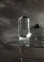 Close view of one glass cylinder from this Clérachic pendant fitted with its black LED cap on a glass table.